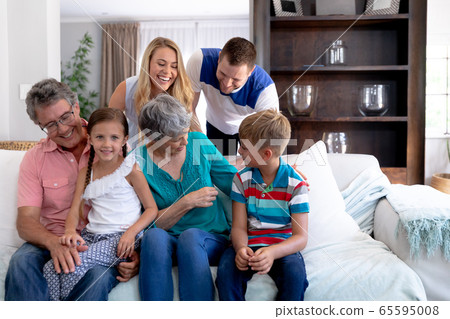 Portrait of a three generation Caucasian family sitting on a couch at home Portrait of a three generation Caucasian family sitting on a couch at home 65595008