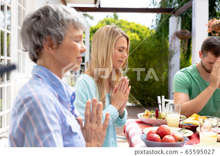 Caucasian three generation family praying during a lunch in the garden Caucasian three generation family praying during a lunch in the garden 65595027