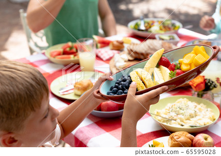Caucasian family sitting at table during a family lunch in the garden Caucasian family sitting at table during a family lunch in the garden 65595028