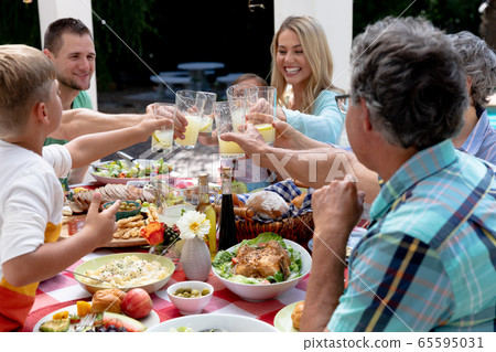 Caucasian family sitting at table during a family lunch in the garden Caucasian family sitting at table during a family lunch in the garden 65595031
