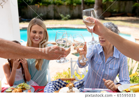 Caucasian family sitting at table during a family lunch in the garden Caucasian family sitting at table during a family lunch in the garden 65595033