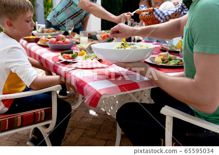 Caucasian family sitting at table during a family lunch in the garden Caucasian family sitting at table during a family lunch in the garden 65595034