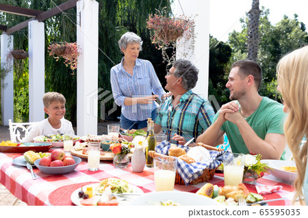 Caucasian family sitting at table during a family lunch in the garden 65595035