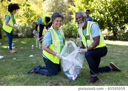 Senior mixed race couple collecting garbage Senior mixed race couple collecting garbage 65595059