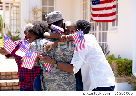 African American male soldier wearing uniform and his family standing by their house African American male soldier wearing uniform and his family standing by their house 65595060