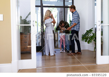 Caucasian family enjoying their time at home greeting a senior Caucasian man Caucasian family enjoying their time at home greeting a senior Caucasian man 65595120