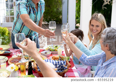 Caucasian family sitting at table during a family lunch in the garden Caucasian family sitting at table during a family lunch in the garden 65595219