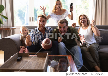 Multi-generation Caucasian family sitting on a couch together and watching a game 65595358