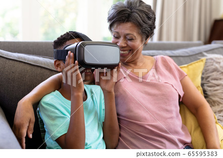 Senior mixed race woman and her grandson at home using VR headset 65595383