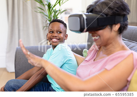 Senior mixed race woman and her grandson at home using VR headset 65595385