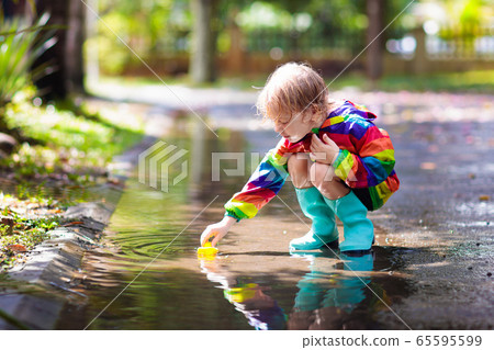 Kids in puddle in autumn rain. Waterproof wear Kids in puddle in autumn rain. Waterproof wear 65595599