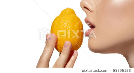 Freshness. Close up of beautiful young woman biting juicy lemon over white background. Cosmetics and makeup, natural and eco treatment, skin care. Flyer, proposal. 65596128