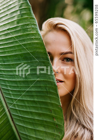Woman in swimsuit on tropical plants background Woman in swimsuit on tropical plants background 65599208