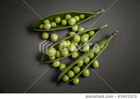 open pea pod with green beans in it. On a dark background . 65601029