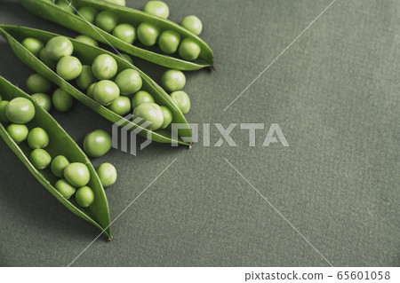 open pea pod with green beans in it. On a dark background . 65601058