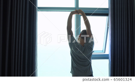 Back of view of young manstretches arms in the morning. 65601324