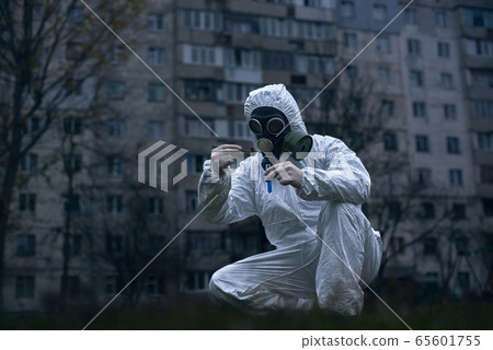 Scientist doing research outdoors, wearing white coverall and gas mask Scientist doing research outdoors, wearing white coverall and gas mask 65601755