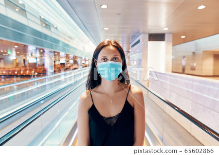 Woman in protection face mask posing in modern shopping mall or airport Woman in protection face mask posing in modern shopping mall or airport 65602866