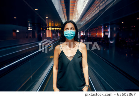 Woman in protection face mask posing in modern shopping mall or airport Woman in protection face mask posing in modern shopping mall or airport 65602867