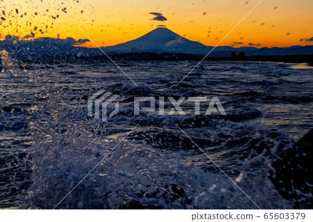 Mt. Fuji and waves splashed in orange at sunset 65603379