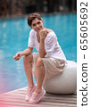 Pretty woman with sort haircut sitting near pool 65605692