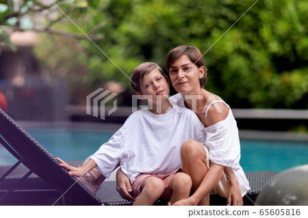 Pretty cheerful young boy hugging his mother Pretty cheerful young boy hugging his mother 65605816