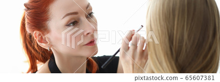Stylish makeup artist does makeup on face blonde 65607381
