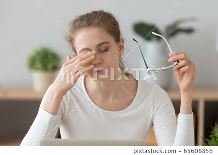 Fatigued girl taking off glasses rubbing eyes feeling eye strain 65608856