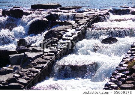 Flow of stone and water of river weir 65609178