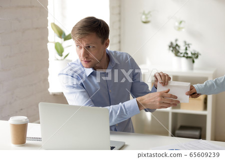 Worried middle aged male manager taking bribe at workplace. 65609239