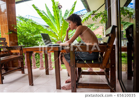 Coronavirus. Quarantine Online training education and freelance work. Computer, laptop and young white man working from home during. COVID-19 pandemic in the world. Side view. Stay at home. 65610035