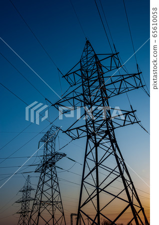 Electric post with wires with sunset background. Transmission tower. Power lines on a colorful sunset. Close up high voltage power lines silhouette. High voltage electric transmission pylon tower. 65610058