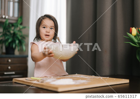 Beautiful little two-year-old girl wearing white dress is holding hands transparent bowl Beautiful little two-year-old girl wearing white dress is holding hands transparent bowl 65611317