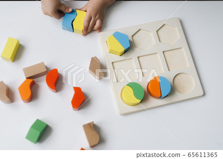 Close-up of hands of unrecognizable little child playing with colorful wooden block toys. 65611365