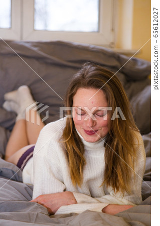 Girl in warm sweater and panties lies across bed Girl in warm sweater and panties lies across bed 65612027