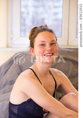 Smiling girl in transparent body suit sits on bed Smiling girl in transparent body suit sits on bed 65612032