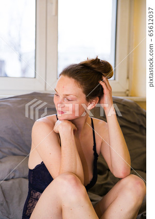 Young blonde lady dressed in blue bodysuit on bed Young blonde lady dressed in blue bodysuit on bed 65612037