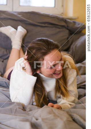 Young woman in knitted sweater and bikini in bed Young woman in knitted sweater and bikini in bed 65612055