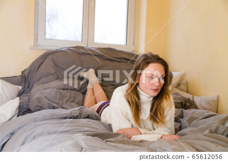 Girl in warm sweater and panties lies across bed Girl in warm sweater and panties lies across bed 65612056