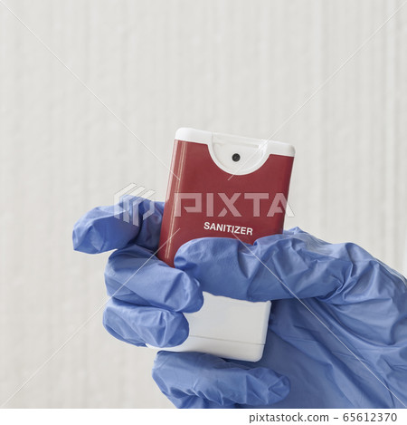 Personal hand sanitizer gel in a hand in a protective blue glove Personal hand sanitizer gel in a hand in a protective blue glove 65612370