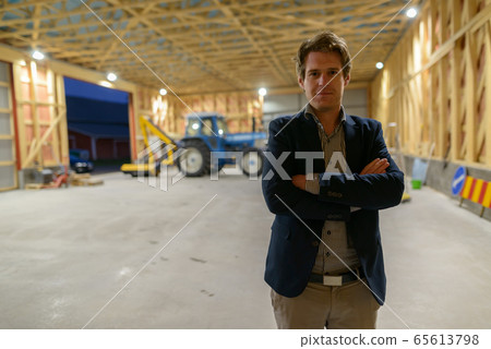Young handsome businessman with arms crossed inside wooden construction site 65613798