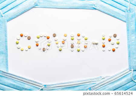 covid-19 inscription with pills and capsules and a blue disposable medical protective mask layout on a white background copy space. Coronavirus, medicine and health, safety concept. covid-19 inscription with pills and capsules and a blue disposable medical protective mask layout on a white background copy space. Coronavirus, medicine and health, safety concept. 65614524