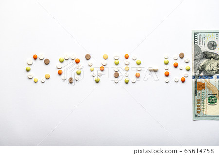 covid-19 inscription with pills and capsules and 100 dollar bill in layout on a white background copy space. Coronavirus, medicine and health, safety concept. 65614758