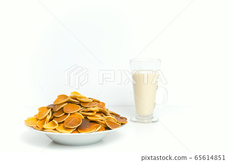 Trendy pancake cereal meal with milk on white background. Tiny baked pancakes. Breakfast food. Trendy pancake cereal meal with milk on white background. Tiny baked pancakes. Breakfast food. 65614851