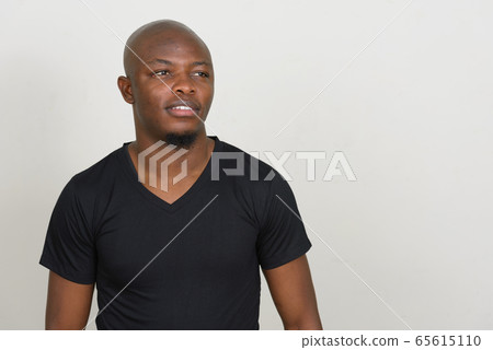 Happy young handsome bald African man thinking Happy young handsome bald African man thinking 65615110