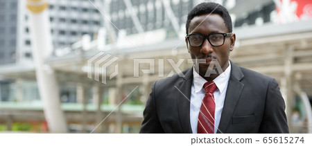 Young handsome African businessman standing in front of modern building at Bangkok city Young handsome African businessman standing in front of modern building at Bangkok city 65615274