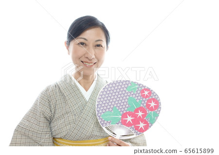A middle-aged woman in a kimono with a smile and a fan with a cool smile A middle-aged woman in a kimono with a smile and a fan with a cool smile 65615899