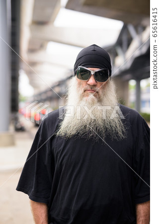 Mature bearded hipster man with sunglasses in the city streets outdoors 65616415