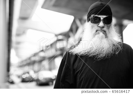 Face of mature bearded hipster man with sunglasses in the city streets outdoors in black and white Face of mature bearded hipster man with sunglasses in the city streets outdoors in black and white 65616417