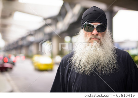 Face of mature bearded hipster man with sunglasses in the city streets outdoors Face of mature bearded hipster man with sunglasses in the city streets outdoors 65616419